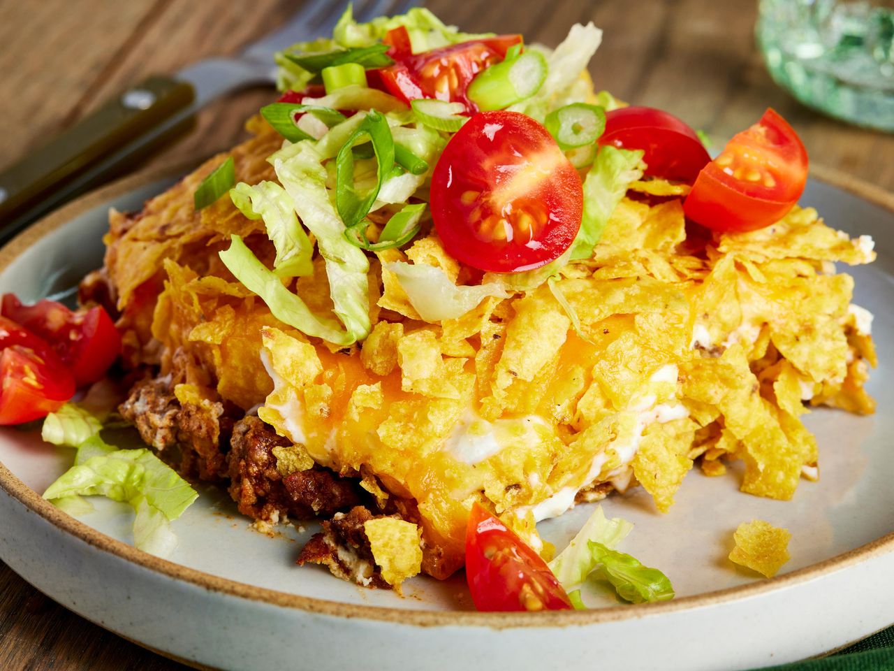 Slice of taco pie on a plate topped with lettuce and tomatoes.