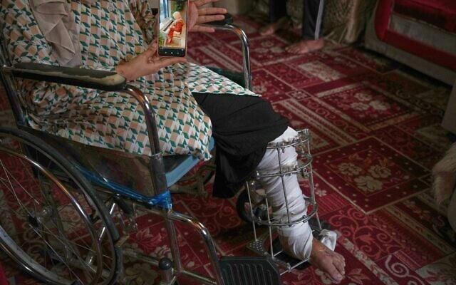 Haneen al-Mabhouh, 34, who lost her leg in an Israeli strike on her home that also killed all four of her daughters, including her 5-month-old baby, shows a photo of one of her daughters on a cellphone while sitting in a wheelchair in her family home in Nuseirat, central Gaza Strip, Thursday, Nov. 6, 2025. (AP Photo/Abdel Kareem Hana)