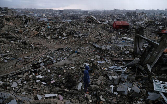 A man walks through the rubble amid stormy weather in Gaza City, December 11, 2025. (AP Photo/Jehad Alshrafi)