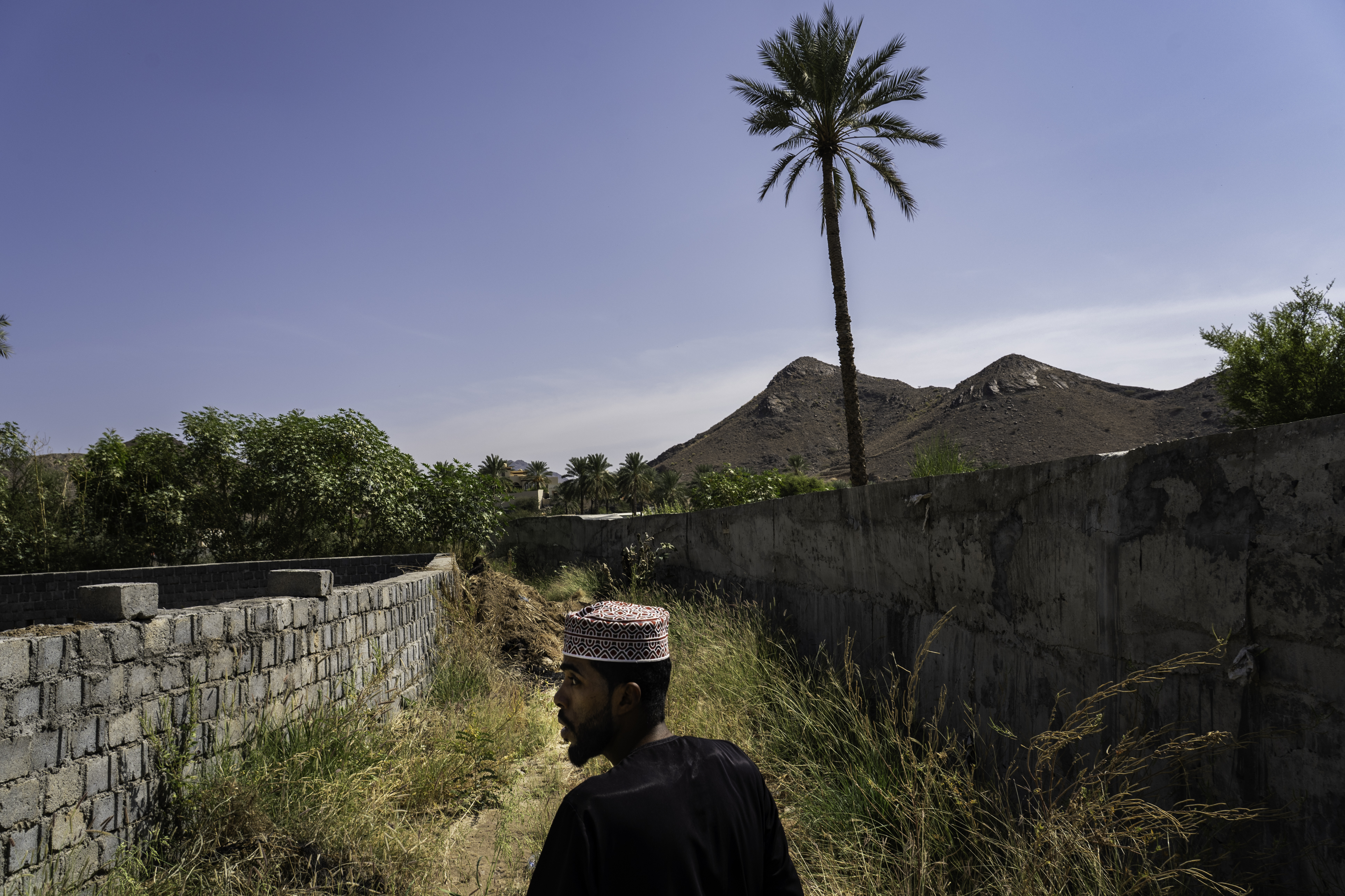 Mohammed Alem Yousuf walks past walls that he help built with locals to protect farms from floodwater.