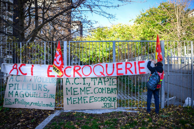 Un employé du groupe ACI accroche une banderole sur une clôture avec les mots "ACI, fraude" lors d'un rassemblement devant le tribunal de commerce à Lyon, dans le centre-est de la France, le 9 décembre 2025, à l'occasion d'une audience concernant les dettes du groupe industriel.