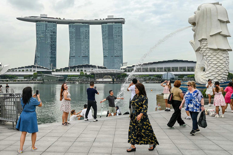 Люди собираются рядом со статуей Мерлиона перед курортом Marina Bay Sands в Сингапуре. В этом году город-государство казнило 17 заключённых — это самый высокий годовой показатель с 2003 года. Фото: AFP