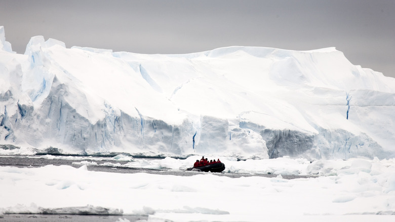 A group of people in an inflatable raft near an ice shelf in Antarctica