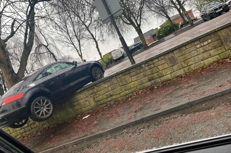 Car pictured balancing on wall after 'rolling back through car park'