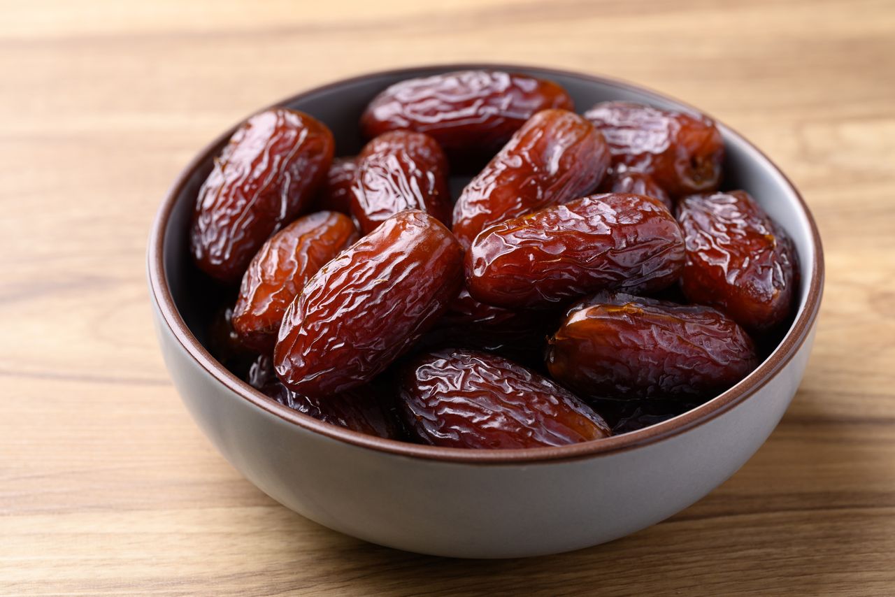 Date palm fruit (MedJool) in bowl on wooden background