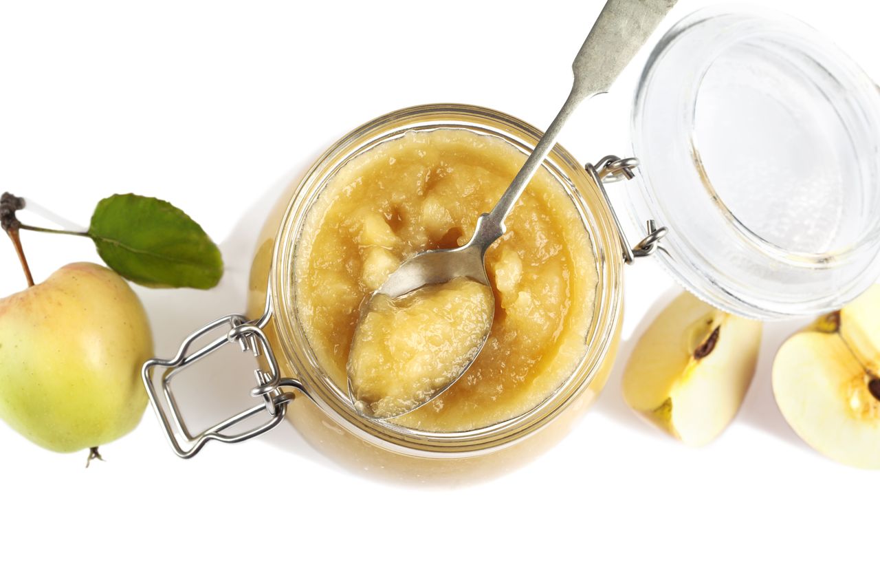 Apple sauce in jars on white background, top view.