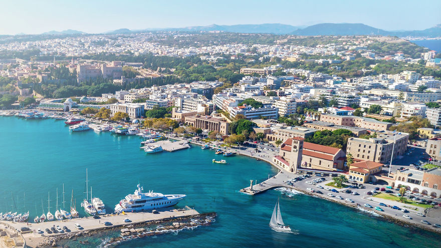 Aerial view of coastal city with clear blue water and boats, representing forgotten 7 wonders of the ancient world prime.