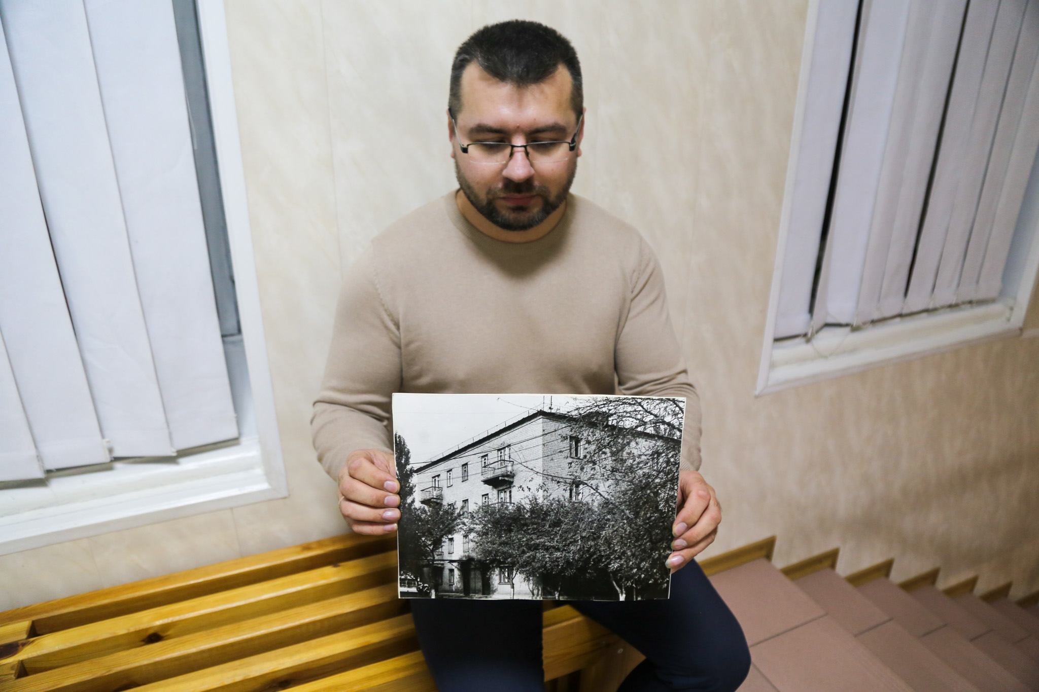 Yevhenii Hryhorovych, director of the Leontovych music school, holds an archive image of the original school building. The newer building has been largely destroyed and students now study online or hours away in the city of Dnipro, where the school is operating in exile. (Siobhán O'Grady/The Washington Post)
