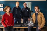 Das Ermittler-Team steht im Büro um den Schreibtisch herum, Feldmann hält eine Backstage-Filmklappe in der Hand. Von links: Ina Behrendsen (Julia Brendler), Carl Sievers (Peter Heinrich Brix), Polizist Schneider (Stephan A. Tölle) und Hinnerk Feldmann (Oliver Wnuk)