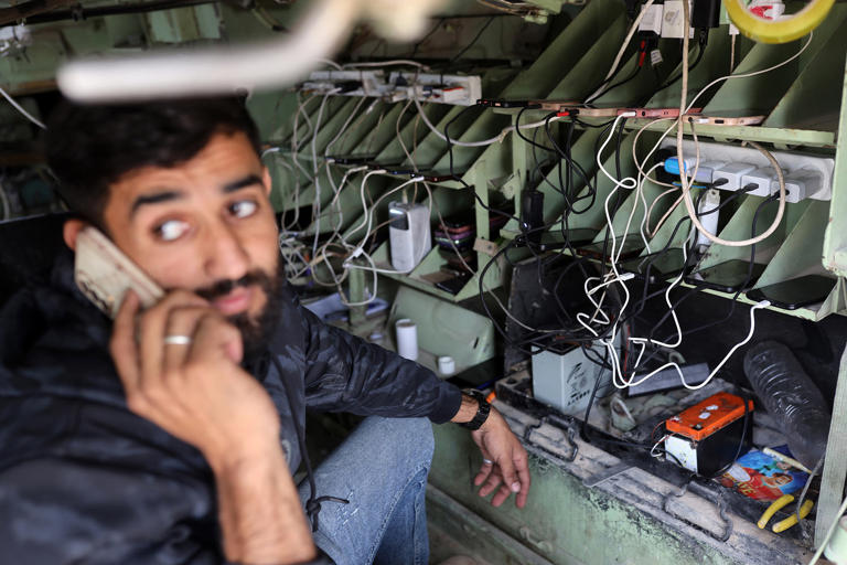 Cellphones connected to wires in mobile charging station in an abandoned Israeli tank in Gaza City. (Majdi Fathi / NurPhoto via AP)