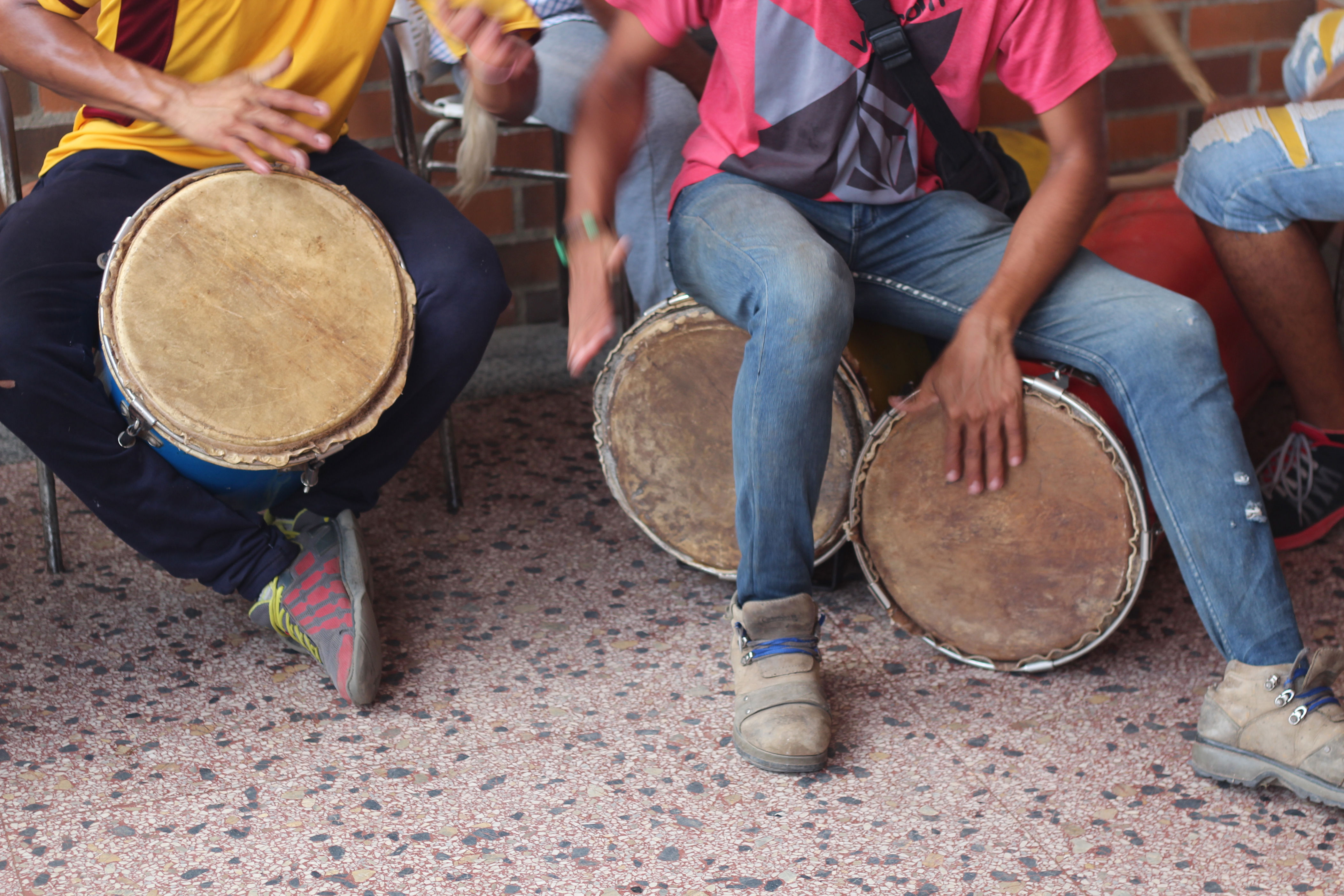 People playing hand drums while sitting on chairs