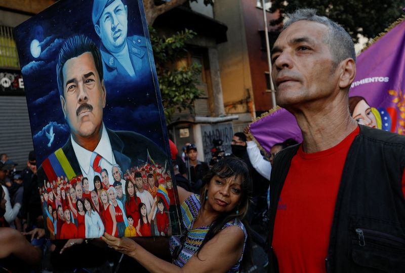 Um apoiador do presidente da Venezuela, Nicolas Maduro, segura uma pintura dele e do falecido presidente Hugo Chávez, durante protesto pedindo a libertação de Maduro, em Caracas, Venezuela, em 4 de janeiro de 2026. REUTERS/Fausto Torrealba