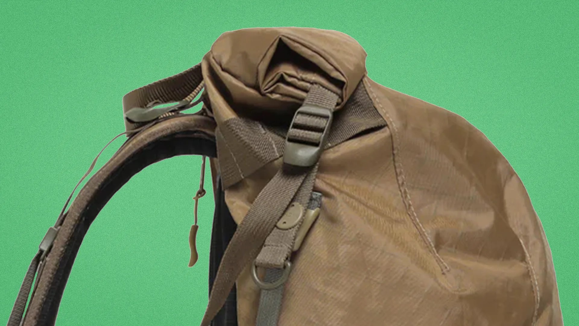 Brown roll-top backpack with adjustable strap and buckle on a green background.