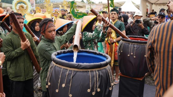 Prosesi ritual pengambilan air suci dari Tuk Sikopyah, yakni menuangkan air di dalam lodong ke guci untuk diperebutkan oleh masyarakat.