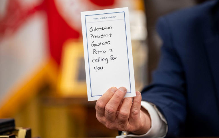 Mr Trump holds up a note given to him by an aide during the interview - Doug Mills/ The New York Times