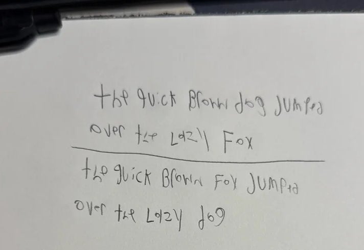 Two handwritten lines on paper: "The quick brown fox jumps over the lazy dog," repeated twice