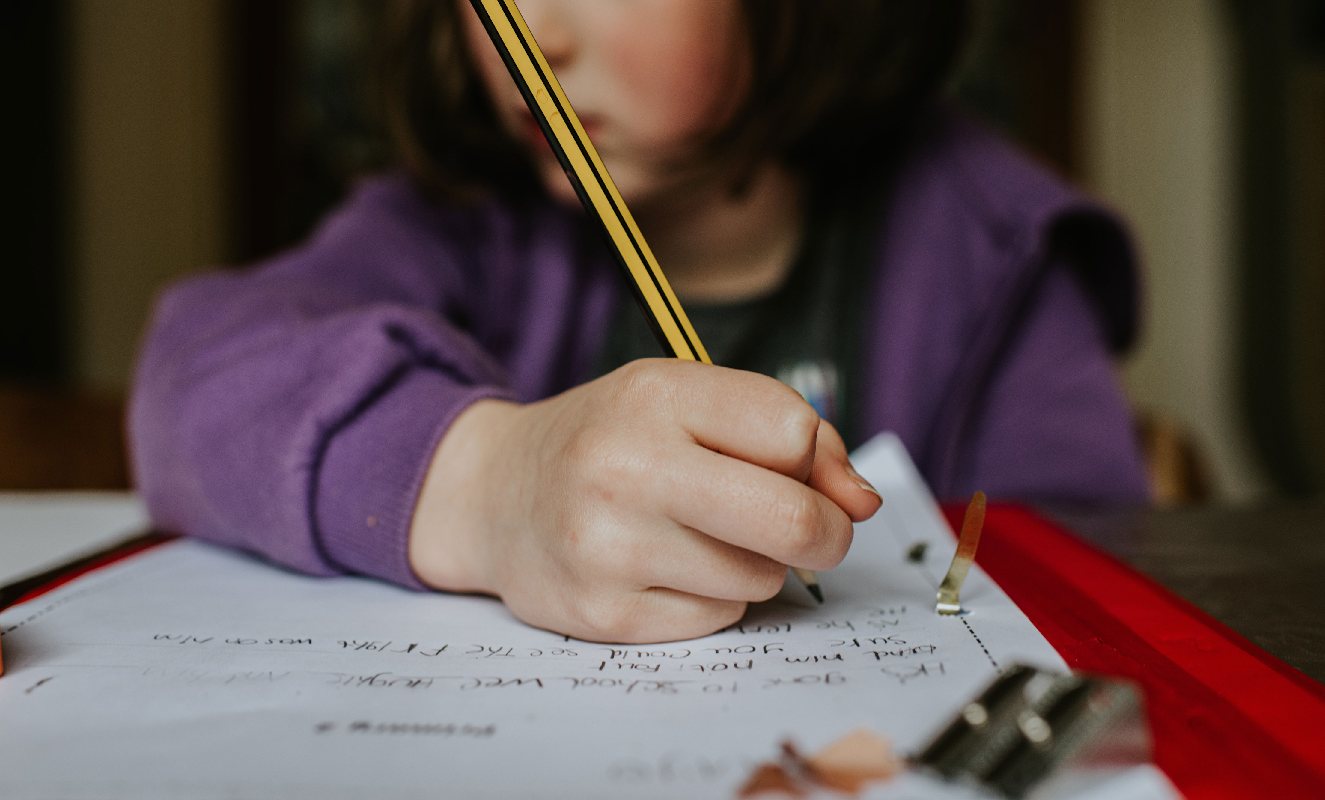 Child writing on paper with pencil, focusing intently