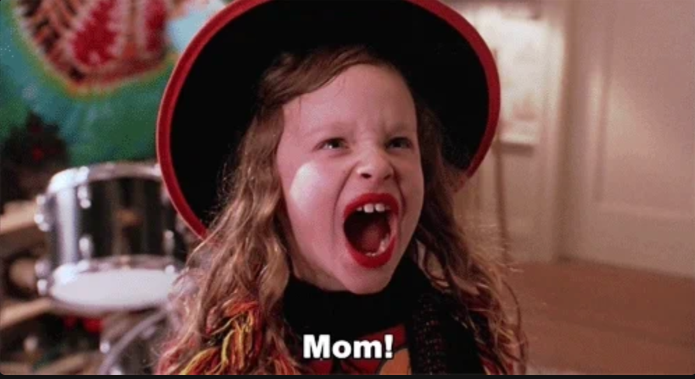 Child in playful costume excitedly shouts "Mom!" with wide smile indoors