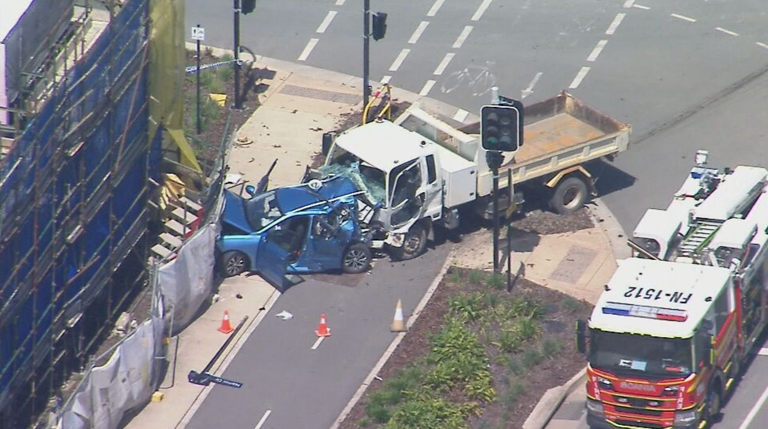 The blue car became trapped between the dump truck and a construction site.