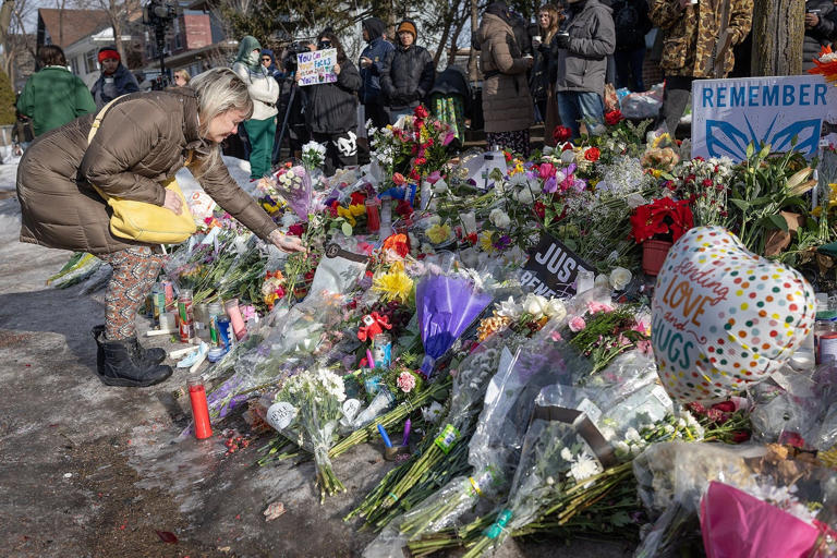 Jacqui Juvland, lays flowers at a growing memorial for Renee Nicole Good, 37, near the corner of 34th and Portland where she was shot and killed by an Immigration and Customs Enforcement (ICE) agent, in Minneapolis, MN on Friday, Jan. 9, 2026.