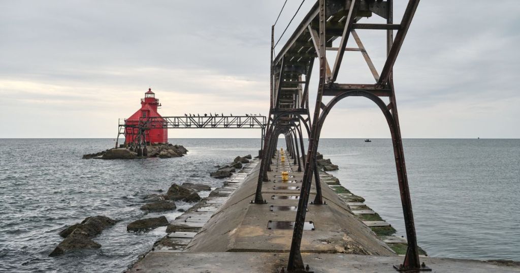 A red lighthouse and a concrete path leading to it.