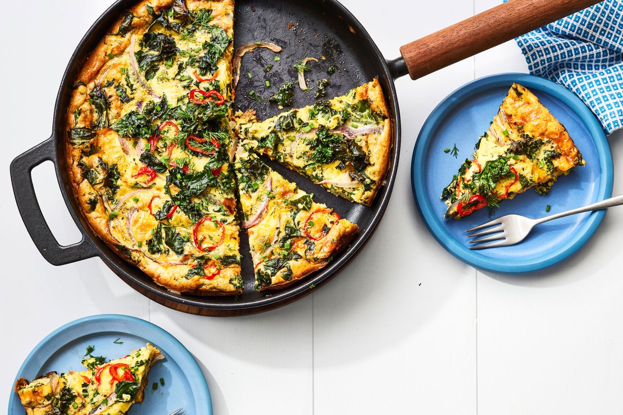 Southern Living Farmersâ Market Frittata in the pan with a couple of slices cut out on blue plates