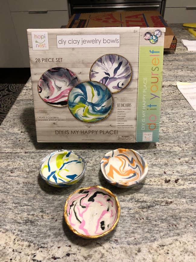 DIY clay jewelry bowl kit with four finished bowls, featuring swirled patterns. Box highlights a 28-piece set for creative home projects