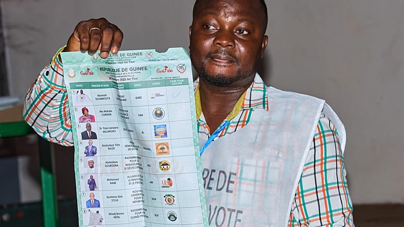 Un responsable brandit un bulletin de vote dans un bureau de vote à la fermeture des urnes lors de l'élection présidentielle à Conakry, en Guinée, le dimanche 28 décembre 2025