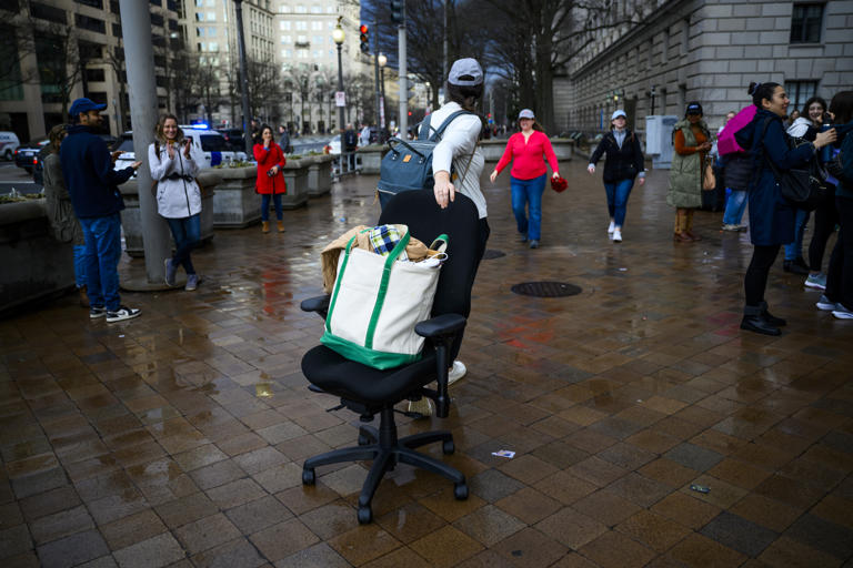 A USAID employee pulls a desk chair as she leaves the agency’s former offices on Feb. 27, in Washington. Employees were given a brief period of time to collect their belongings and vacate the building.