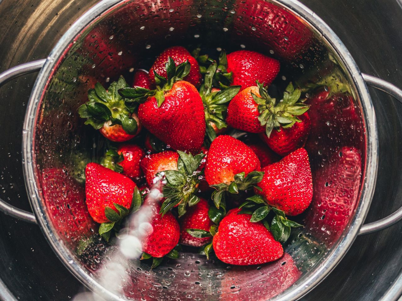rinsing strawberries in a colander