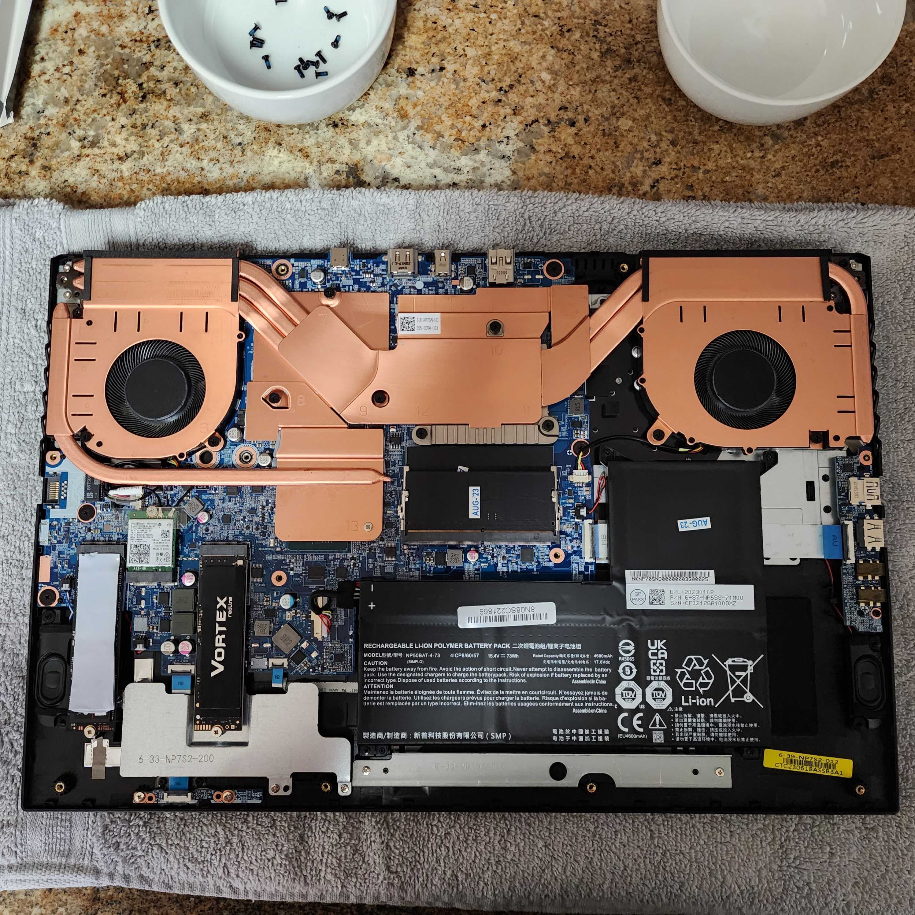 A laptop open on a table with two SSDs installed in its M.2 slots.