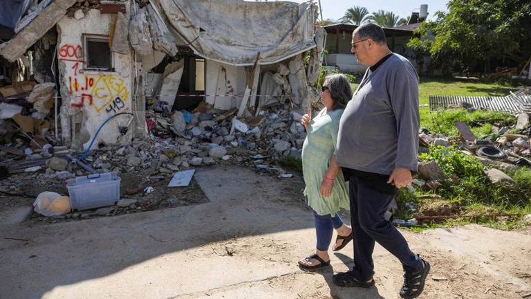 Ayelet Khon and Shar Shnurman walk past the remains of a home that was destroyed following the October 7 attack, in southern Israel, January 13, 2024. - Amir Cohen/Reuters