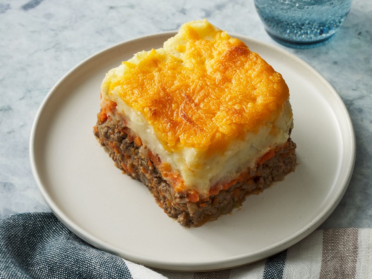 A square serving of shepherds pie on a white plate