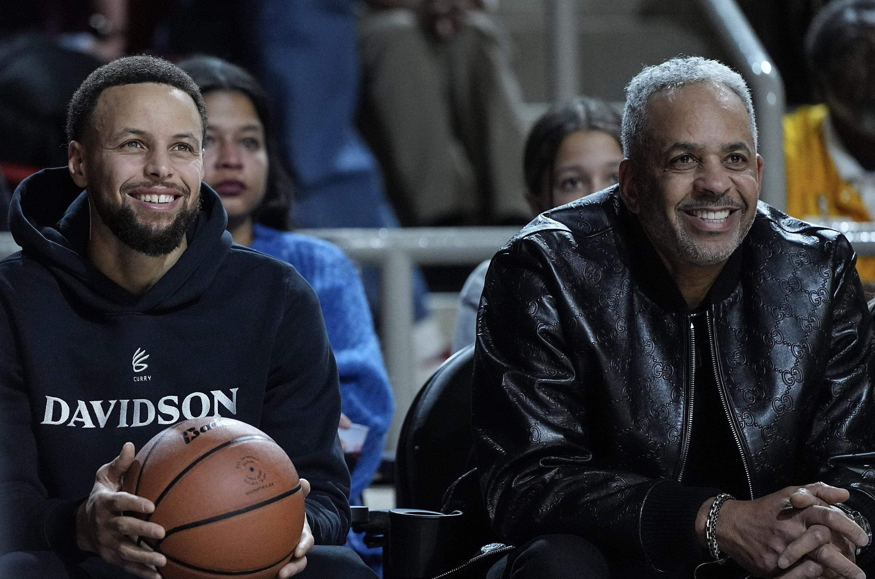 Golden State Warriors guard and Davidson alumni Stephen Curry, left, sits next to his father Dell Curry during the first half of Tuesday's game between Davidson and Duquesne at Belk Arena.