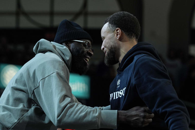 Golden State Warriors guard and Davidson alumni Stephen Curry, right, embraces teammate Draymond Green during halftime of Tuesday's college basketball game between Davidson and Duquesne at Belk Arena.