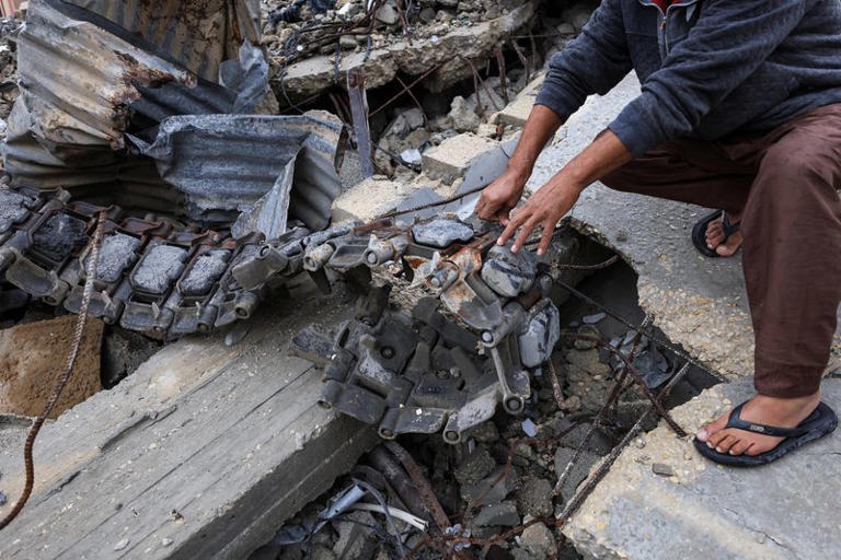 Hesham Badawi, a Palestinian, next to debris from an armoured personnel carrier, next to destroyed buildings after Israeli military operations in Gaza City, November 25, 2025. REUTERS/Dawoud Abu Alkas