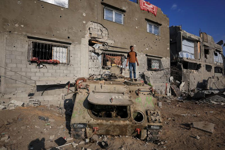 A Palestinian stands on an armoured personnel carrier next to destroyed buildings after Israeli military operations in Gaza City, November 12, 2025. REUTERS/Dawoud Abu Alkas