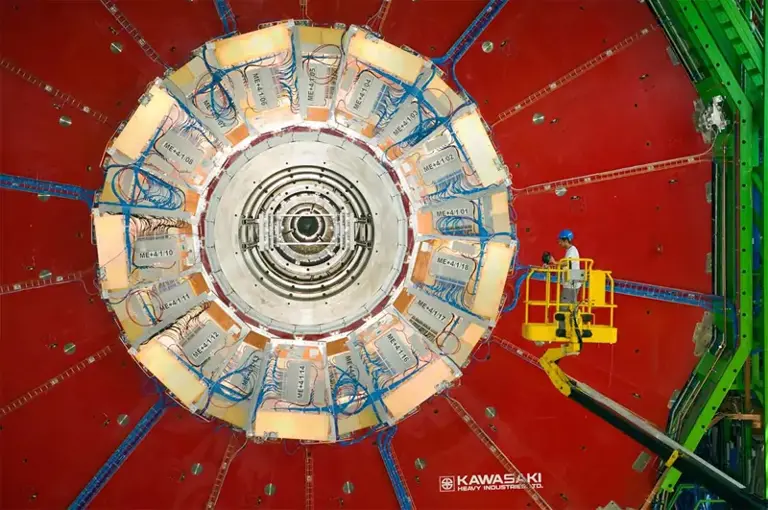 Um solenóide de muão compacto (CMS), que, apesar do seu nome, é um enorme detector de partículas do Grande Colisor de Hadrões (LHC) no CERN, a ser utilizado para procurar o bosão de Higgs. O LHC no CERN ocupa um túnel circular subterrâneo com quase 27 quilómetros de circunferência.