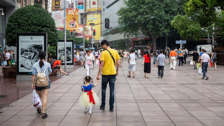 A family walks through the Nanjing Road shopping district in Shanghai in 2016. - Qilai Shen/In Pictures/Getty Images