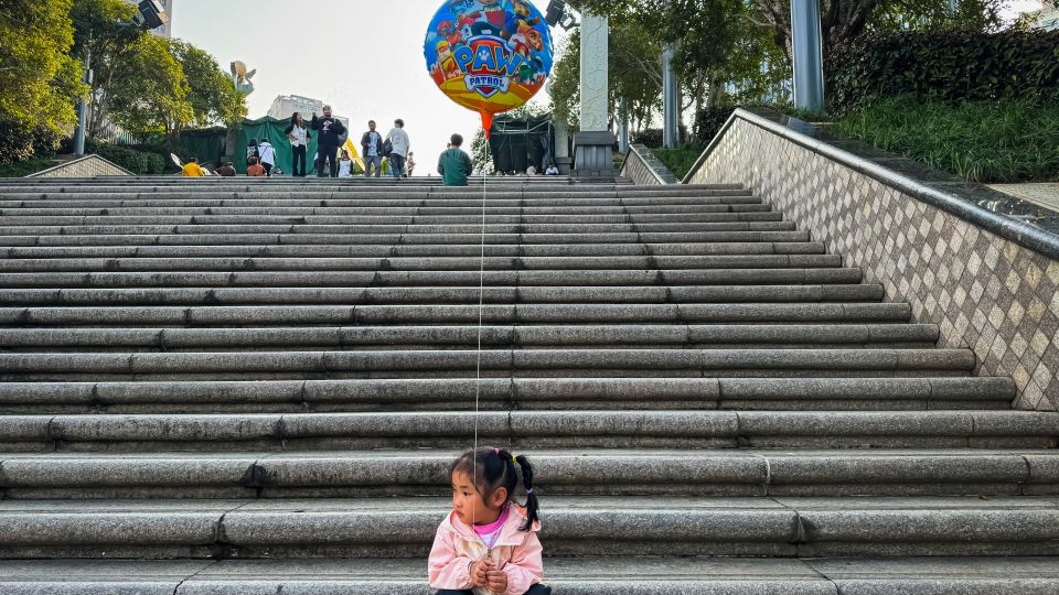 A young girl sits alone on a set of steps in the megacity of Chongqing in 2024. - Cheng Xin/Getty Images