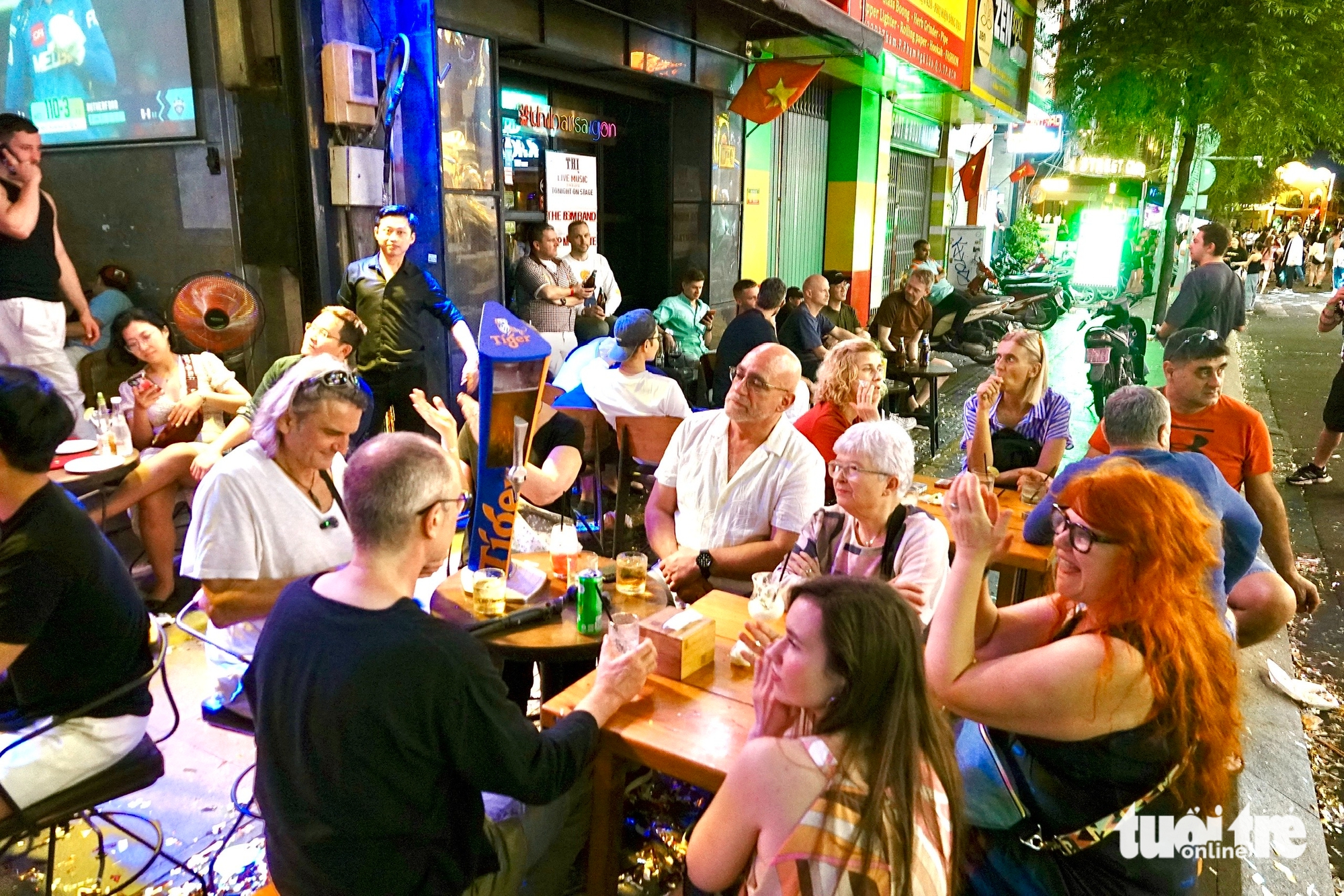 Nhóm khách ngồi uống bia đón năm mới tại quán nhạc trên đường Đề Thám, phường Bến Thành, TP.HCM trong dịp năm mới 2026 - Ảnh: T.T.D.