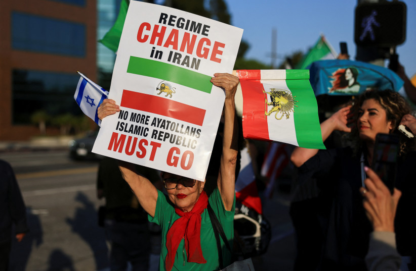 A demonstrator holding an Israeli flag and an Iranian flag from the reign of Shah Mohammed Reza Pahlavi takes part in a protest against the Iranian government outside the Federal Building in Los Angeles, California, US June 23, 2025. (credit: REUTERS/DAVID SWANSON)
