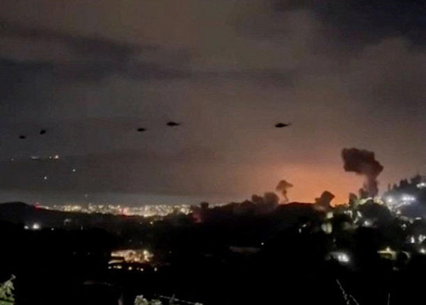 Helicopters fly past plumes of smoke rising from explosions, in Caracas, Venezuela, January 3, 2026 in this screen grab obtained from video obtained by Reuters.