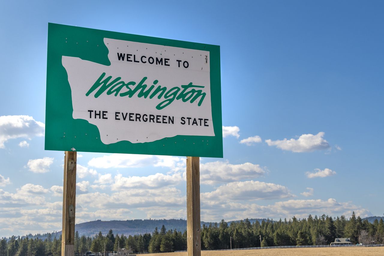 Washington state road sign with mountains, forest and plains in the background