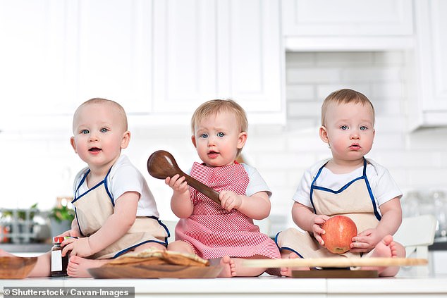 three toddlers sitting on a kitchen bench playing with kitchen utensils (file photo)