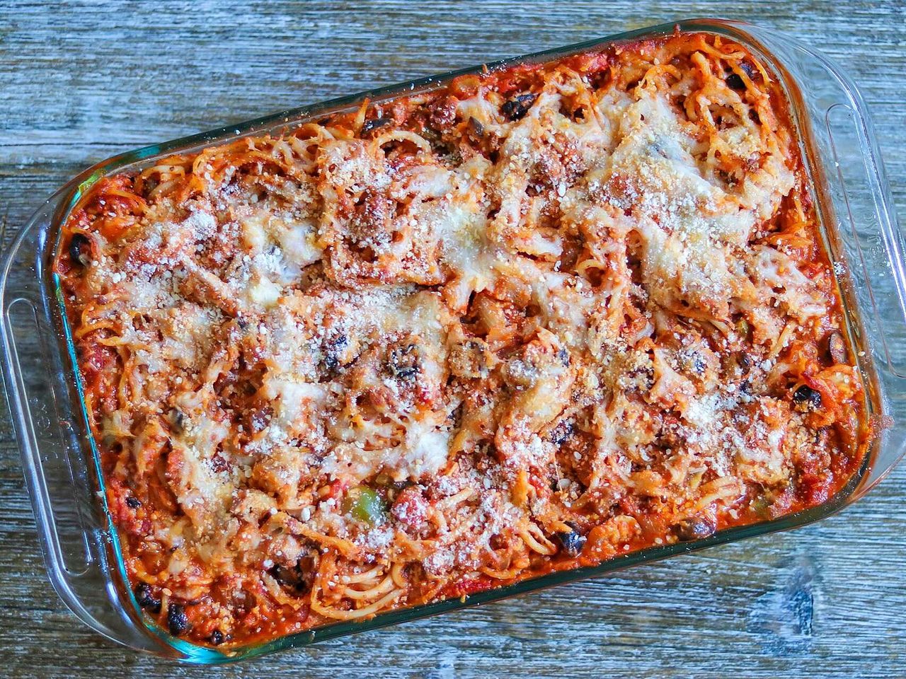 spaghetti bake with melted cheese in glass casserole dish