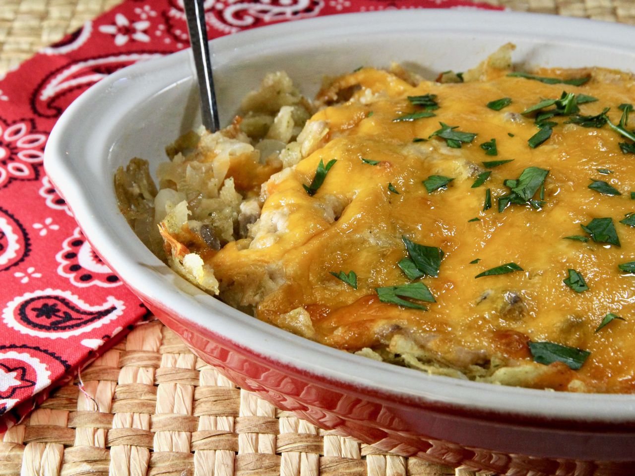 Cheesy onion casserole in casserole dish on paisley patterned cloth
