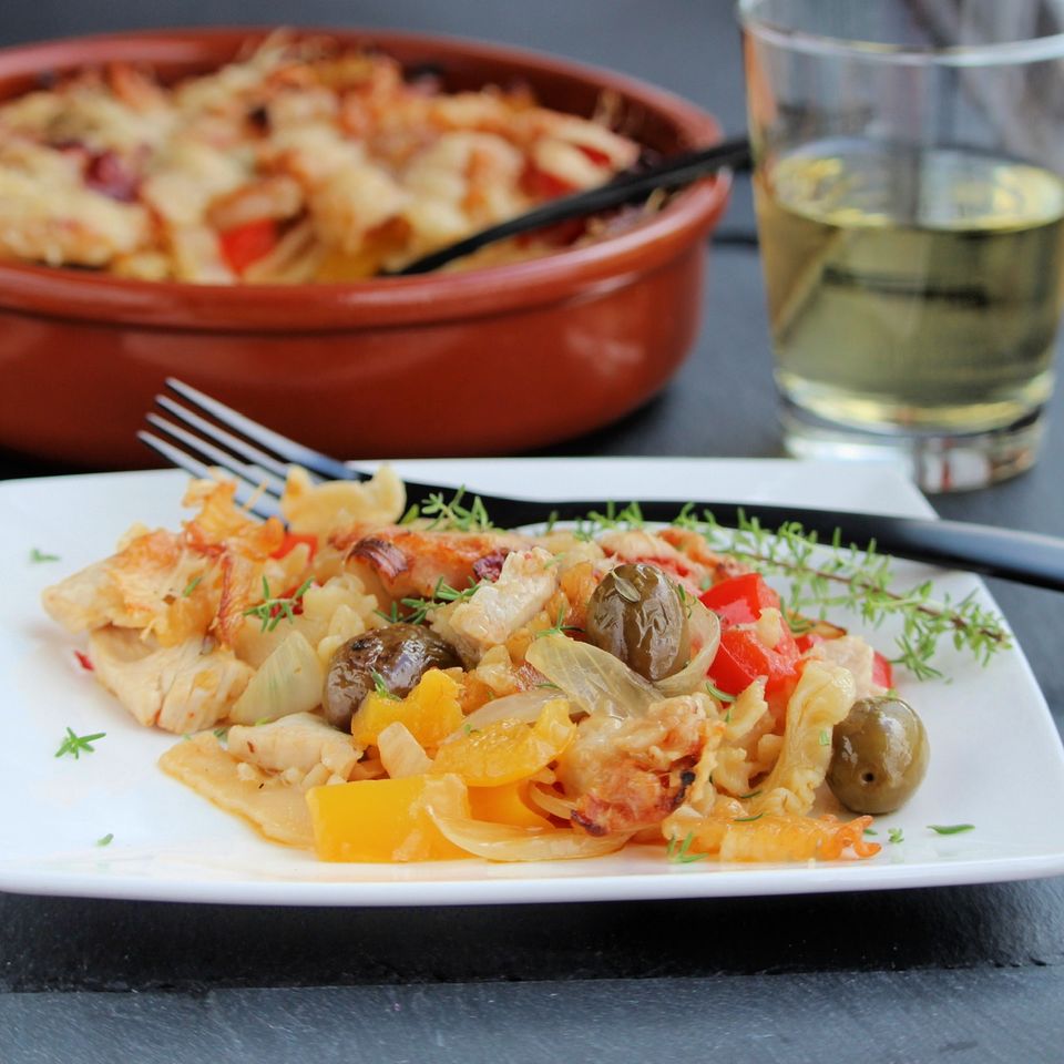 a colorful serving of casserole on a white plate with a baking dish in the background