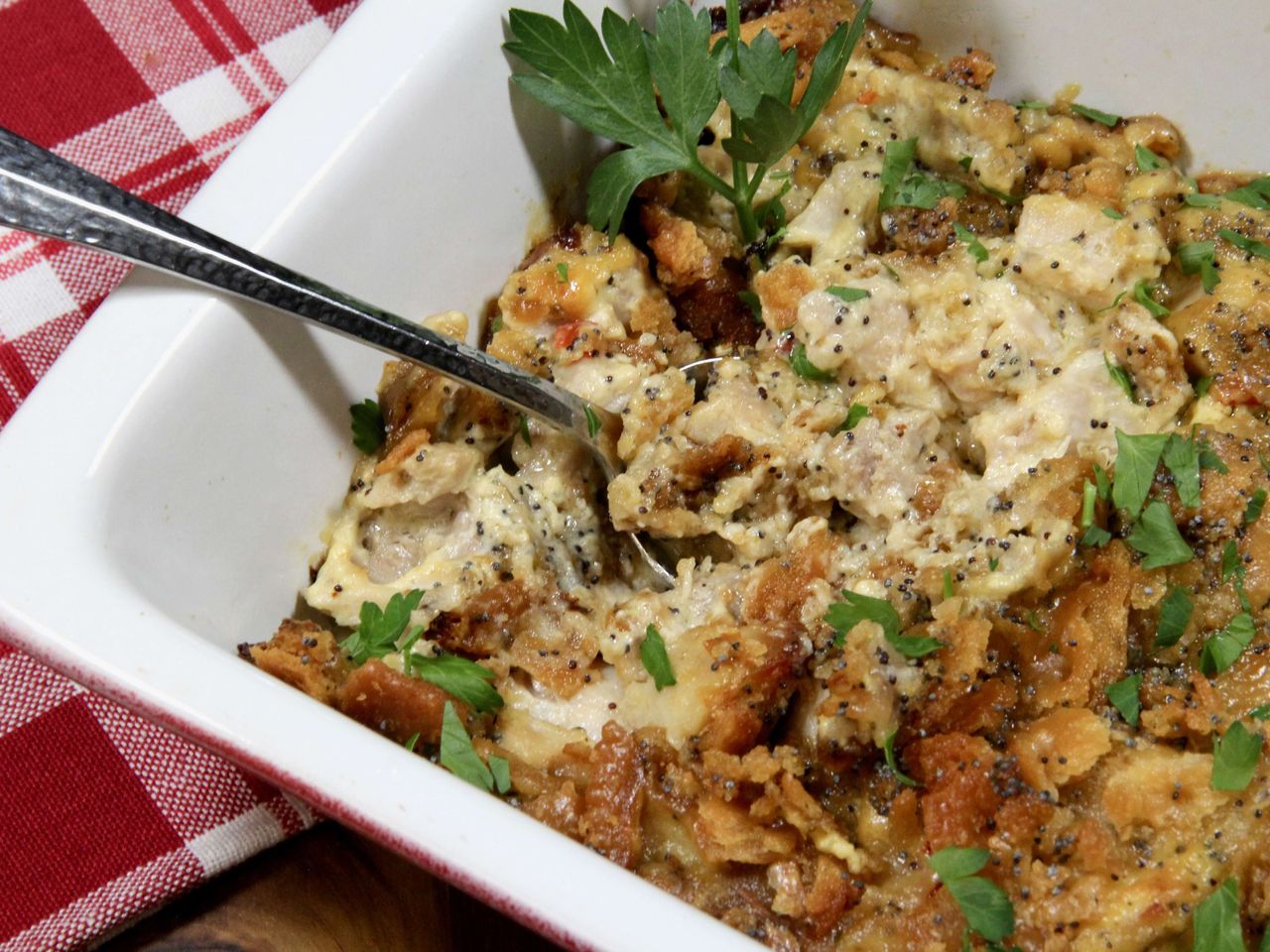 Chicken casserole with poppy seeds garnished with parsley in casserole dish