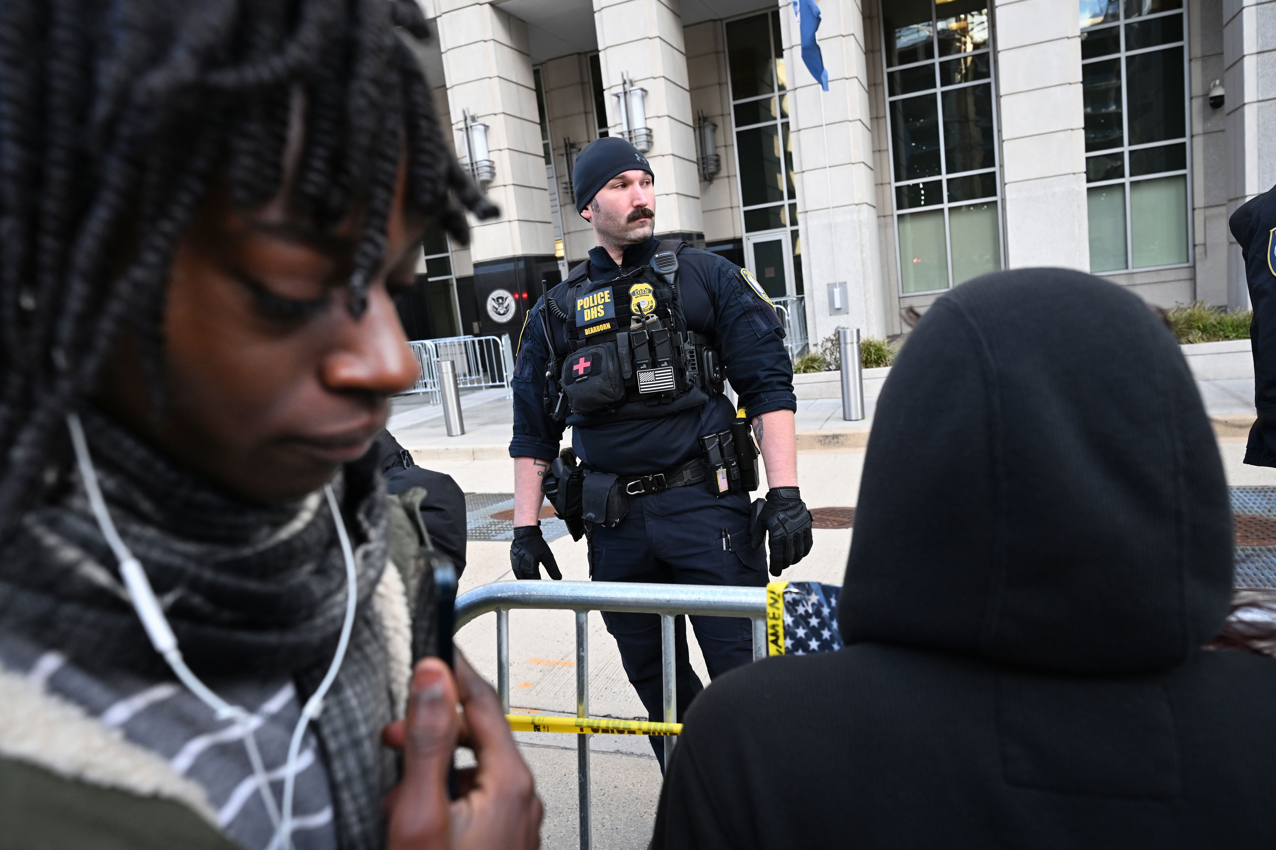 Department of Homeland Security personnel watch as people gather outside the U.S. Immigration and Customs Enforcement building on Sunday.